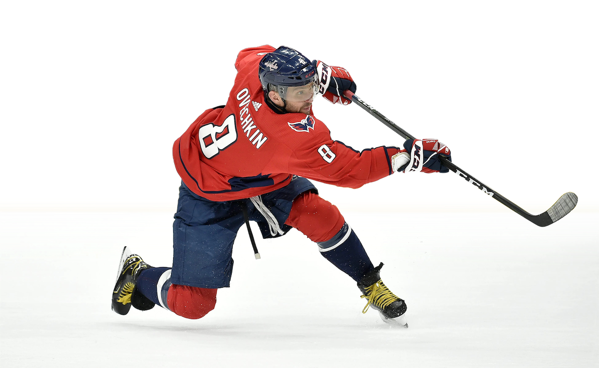 The same action shot of the hockey player, Alexander Ovechkin #8 (in a red uniform), in the middle of hitting the puck to the right, but the background has been meticulously removed.