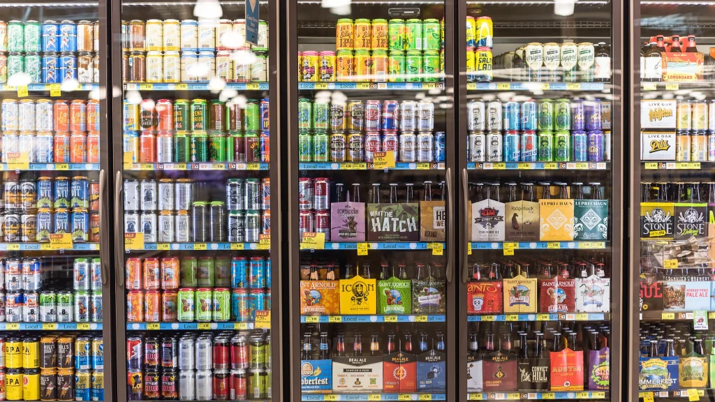 A photo of several cooler doors in a store, showing many shelves of colorful craft beer.