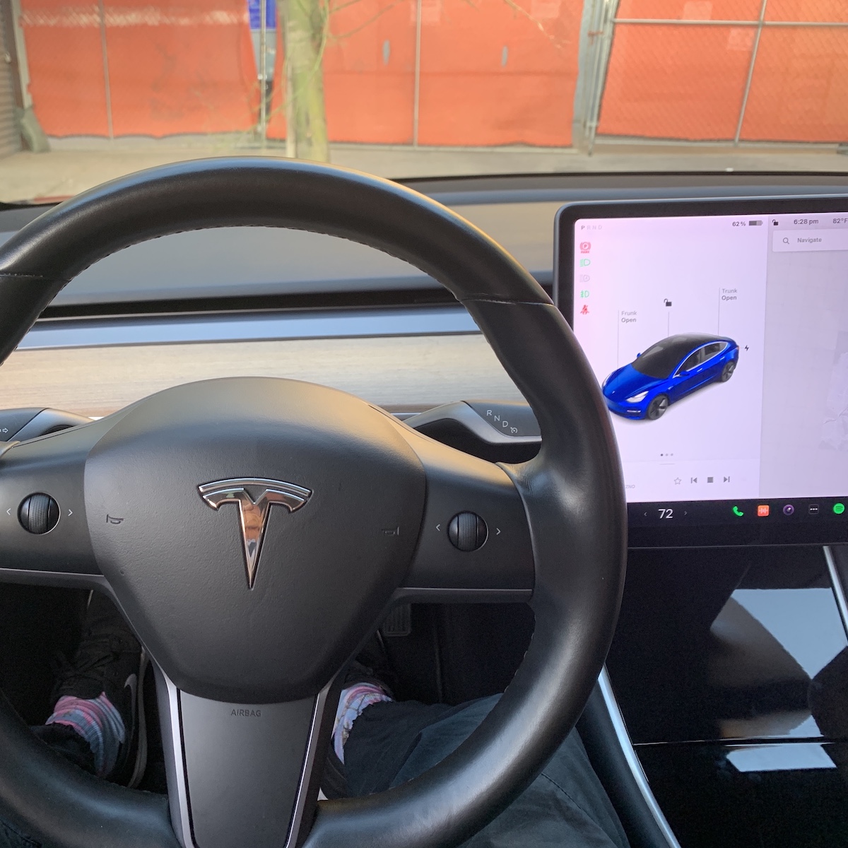 A photo from the driver's seat of a Tesla sedan, showing the steering wheel and dashboard, which features an astonishing lack of any screens or gauges except for the one touch screen in the center